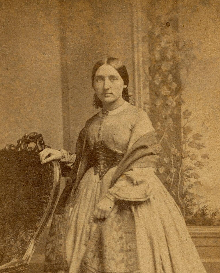 Vintage 1860s carte de visite photograph of a woman standing beside an ornate Victorian chair